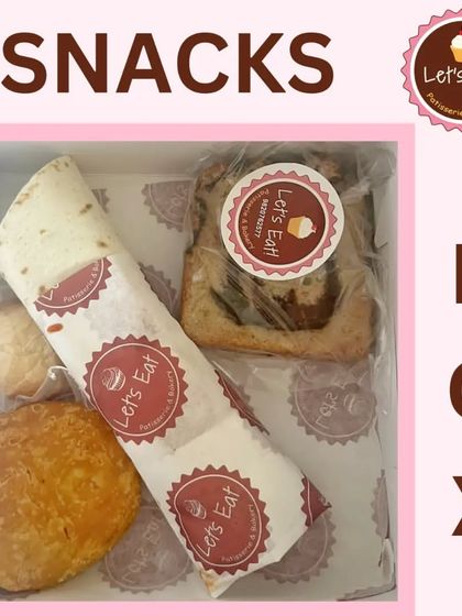 A snack box featuring a savoury wrap, a slice of marble cake, a puff, and a cookie. This option is great for lunch meetings or as a grab-and-go meal.