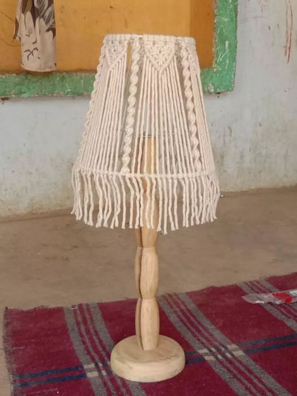 A classic wooden table lamp with a simple macrame shade. This piece combines natural materials to create a timeless decor item for your home.