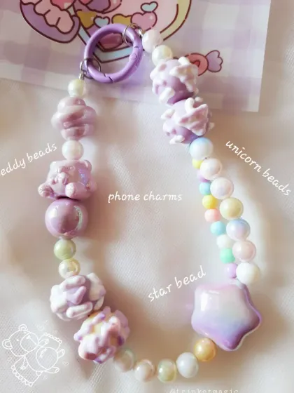 A close-up of the purple phone charm, highlighting the different types of beads used: soft teddy beads, magical unicorn beads, and a pastel star bead.
