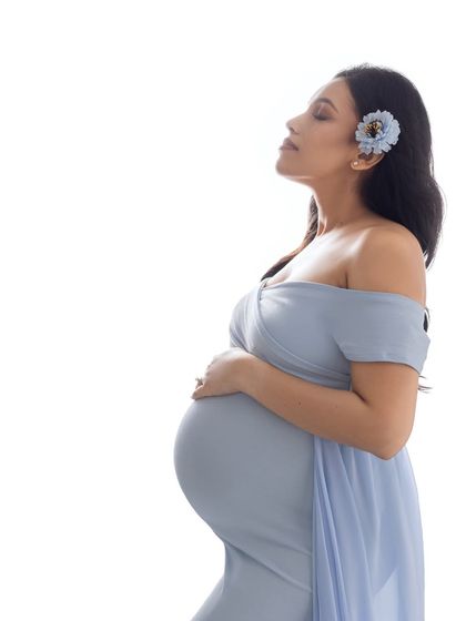 A serene high-key portrait against a pure white background, emphasizing her peaceful expression and the shape of her bump.