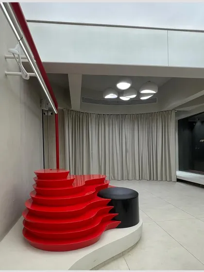 A key feature of the ARKS store is the vibrant red, multi-level display unit. Its organic, flowing shape provides a dynamic platform for showcasing products like shoes and accessories, adding a burst of energy to the minimalist space.