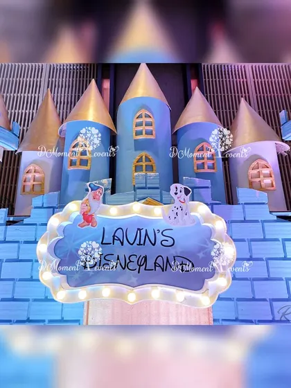 A close-up of the magnificent castle centerpiece at Lavin's Disneyland party. The detailed blue and gold castle features a lighted sign, setting a magical tone for the celebration.