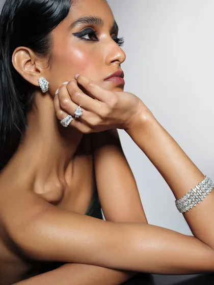 A composition designed to showcase a full suite of diamond jewelry, including a bracelet, rings, and earrings. The model's pose is elegant and classic, perfect for a luxury brand.