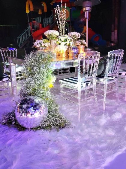 A whimsical and glamorous winter-themed setup with a disco ball and transparent chairs.