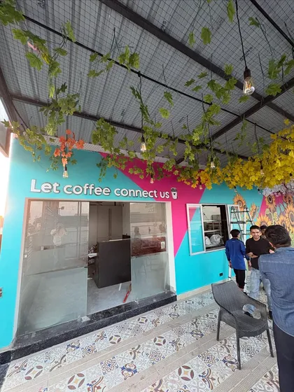A wider view of the cafe's entrance, showcasing the combination of painted walls, 3D lettering, and decorative elements.