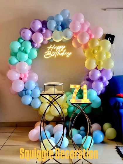 A pastel-colored balloon ring with a 'Happy Birthday' neon sign, creating a soft and beautiful photo spot for a 71st birthday.