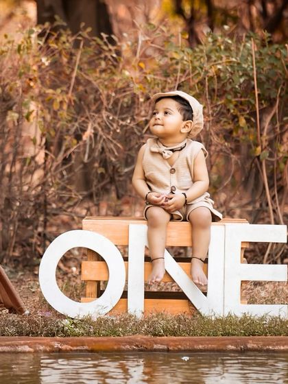 Another angle from the adventurous outdoor first birthday session. The baby looks up thoughtfully, creating a sweet and contemplative portrait amidst the rustic props.