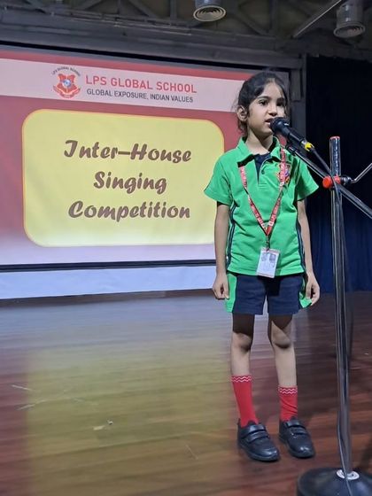 A student from the primary wing sings into the microphone during the singing competition. Our events are designed to give every child a platform to showcase their unique talents.