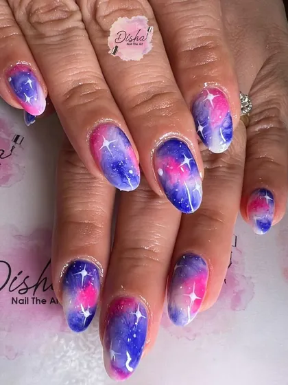 A beautiful pink and purple galaxy nail design with sparkling white stars.