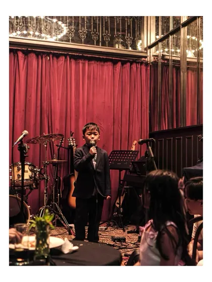 It's never too early to start your journey as a performer. Here's one of our youngest vocal students captivating the audience at a Students' Gig, showing the confidence we build from day one.