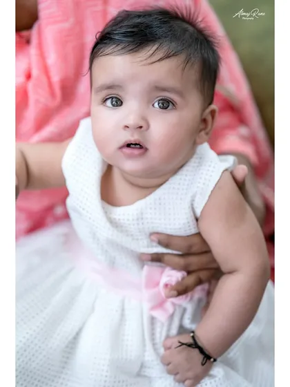 A sweet portrait of baby Navya being held by her mother. This close-up captures her innocent expression and the feeling of safety in a parent's arms.