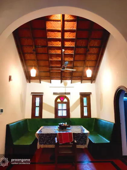 This dining nook in our Udupi project features built-in seating made from red oxide, a classic South Indian flooring and seating material. Paired with a vaulted ceiling of clay tiles and wood, it creates a cozy, nostalgic space for family gatherings.