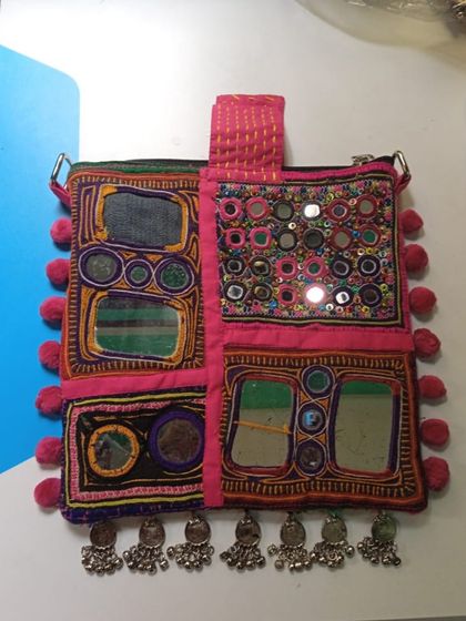 A close-up of a custom-created bag, showcasing intricate mirror work and pom-pom details. This is an example of the unique, handcrafted accessories we love to source and create.
