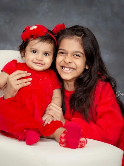 The bond between siblings is so special. This studio portrait of two sisters, coordinated in bright red, showcases that sweet and happy connection that I love to photograph.