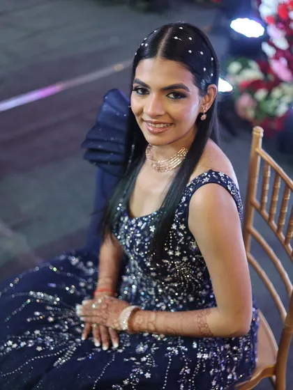 Ready for her reception in a stunning navy blue gown. I created a dramatic smokey eye and kept the skin luminous to balance the look, complemented by a sleek, pearl-studded hairstyle.
