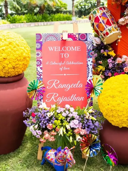 The welcome signage for our "Rangeela Rajasthan" event, framed by large pots of marigolds and colorful pinwheels. It set the tone for a colorful celebration of love from the moment guests arrived.