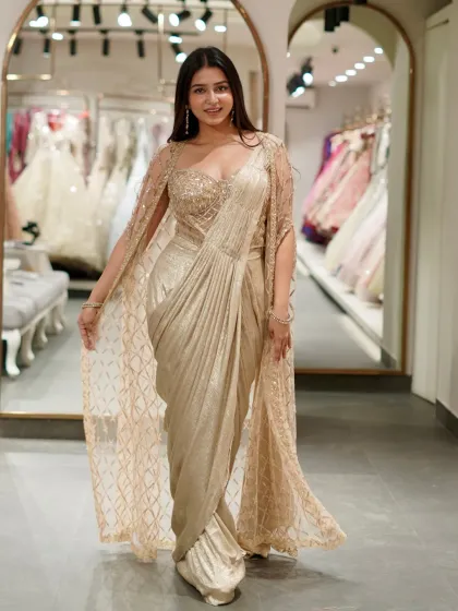 Get all the glamour of a saree without the fuss. This golden pre-draped saree comes with a stunning sequined bustier and a matching embellished cape, giving you a showstopper look in minutes.