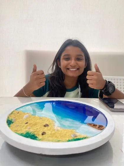 A young participant gives a thumbs-up with her completed resin beach art. My workshops are fun for all ages.