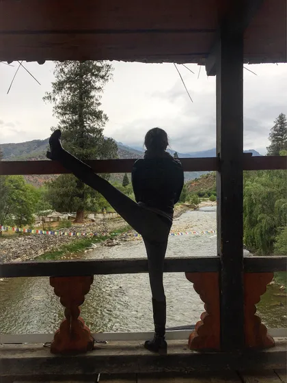 Yoga isn't just for the mat. Here, I'm taking a moment for a standing leg stretch on a bridge during a trek in Bhutan. Our retreats weave mindful movement into every part of the day, encouraging you to find moments of connection and release wherever you are.