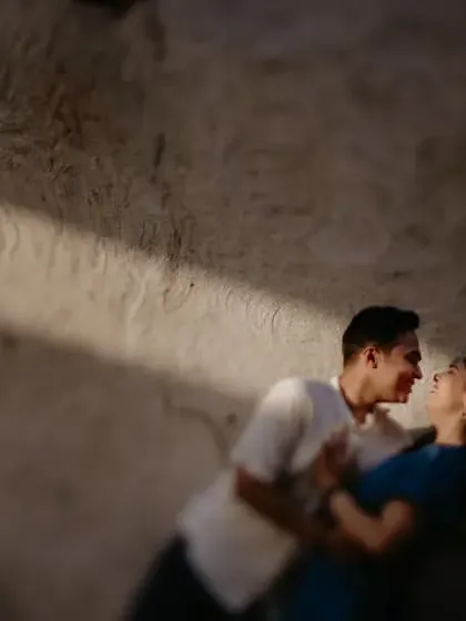 An intimate, blurry shot of a couple about to kiss against a rustic wall in Dubai. The artistic blur and dramatic lighting create a romantic and cinematic feel.