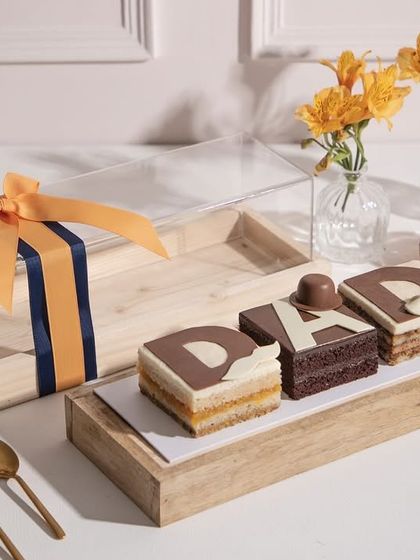 Our "DAD" cake pastries in a clear-lid wooden gift box, tied with a handsome ribbon. A limited edition treat to celebrate the sweetest hero.