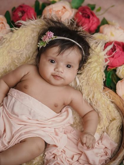 A floral beauty. This older baby is awake and alert, her bright eyes shining as she lies in a bed of flowers.