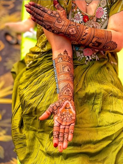 A bride showing off her full-arm mehandi, which features a beautiful portrait on the palm.