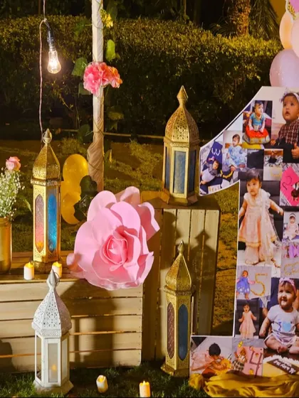 We love adding personal touches to your celebrations. For this first birthday, we created a large number '1' photo collage showcasing the baby's first year, surrounded by rustic wooden crates, lanterns, and paper flowers.
