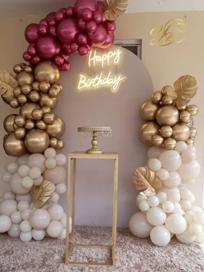 A repeat of the elegant birthday setup with white, gold, and magenta balloons. The golden monstera leaves and neon sign make it a very stylish choice.
