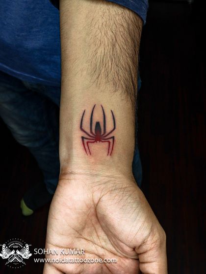 A minimalist Spider-Man logo with red and black ink. This is a great example of how a touch of color can make a simple, graphic tattoo stand out.