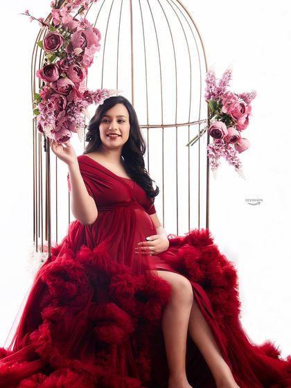 A closer view of the birdcage setup, focusing on the client's happy expression. The combination of the red gown and pink floral accents creates a romantic and cheerful atmosphere.