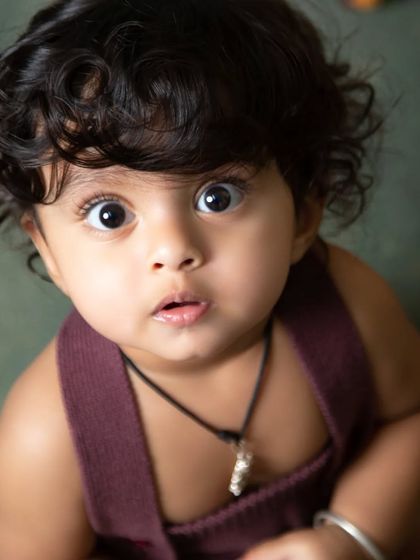 A striking close-up portrait from a jungle-themed session, capturing the baby's beautiful, wide eyes and curly hair.
