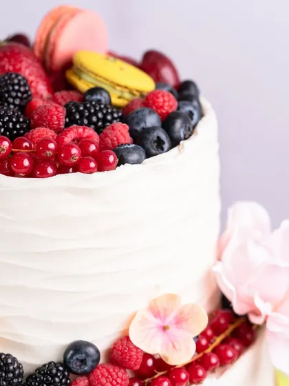 Another detail shot of the two-tiered cake, highlighting the textured buttercream and fresh floral accents.