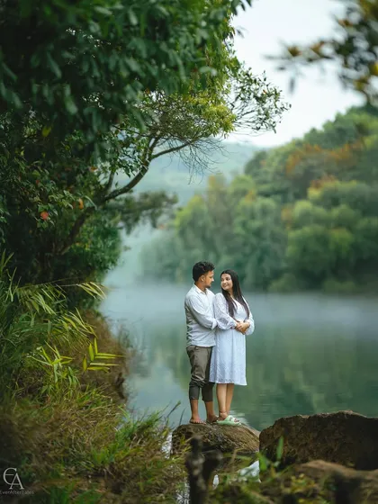 A classic couple portrait on the rocks beside a misty river. The soft light and calm water provide a serene and romantic setting that highlights their gentle connection.