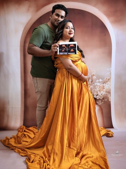 The couple proudly displays their baby's first picture. Holding the ultrasound photo is a deeply personal and meaningful way to include the baby in the maternity shoot.