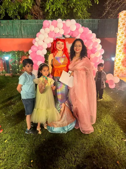 A beautiful mermaid character poses with the birthday girl and her family. This is a great example of a unique character option I can provide for fantasy or princess themed parties.