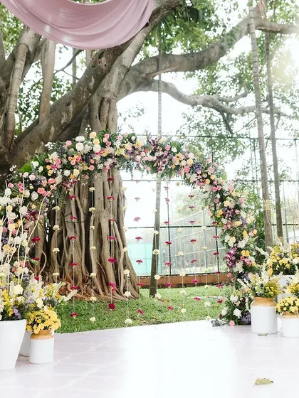 I love using nature as my canvas. For this Haldi, we built a dreamy floral arch right under a magnificent banyan tree, letting the decor feel like a natural extension of the beautiful surroundings.