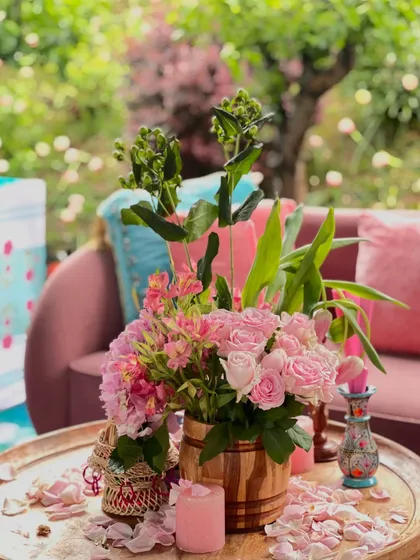 Another angle of the Kashmiri table decor, showing the beautiful pink floral arrangements in a rustic wooden vase, set against the soft pink seating.