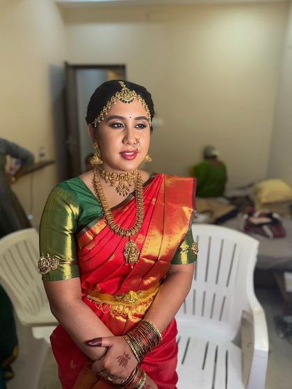 A candid shot of Dr. Indhu in the getting-ready room. Even in a simple setting, her bridal makeup and attire make her look absolutely radiant and ready for her ceremony.
