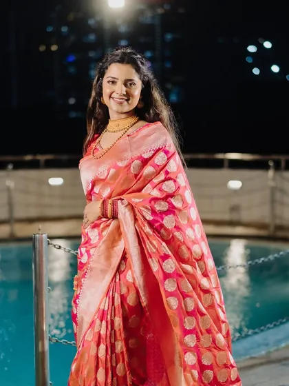 A gorgeous shot by the pool at night. The bride's makeup is flawless, and her pink Banarasi saree looks stunning against the dark background.