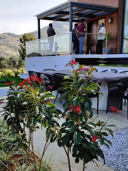 An outdoor dining area on the patio of the Nandi Hills home. This space is perfect for entertaining guests while enjoying the fresh air and beautiful views of the surrounding hills and gardens.