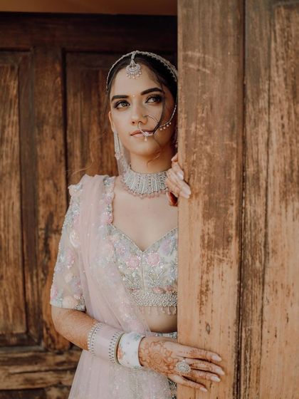 The bride peeks from behind a rustic wooden door, a creative and slightly mysterious portrait.