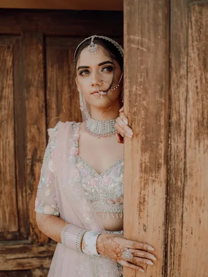 The bride peeks from behind a rustic wooden door, a creative and slightly mysterious portrait.