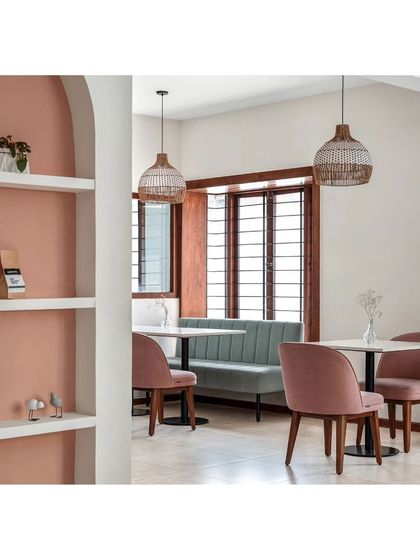 The upper floor of Kana Cafe, where pastel green and peach hues create a soft and inviting atmosphere. The space includes varied seating arrangements, including this cozy nook with a built-in bench.