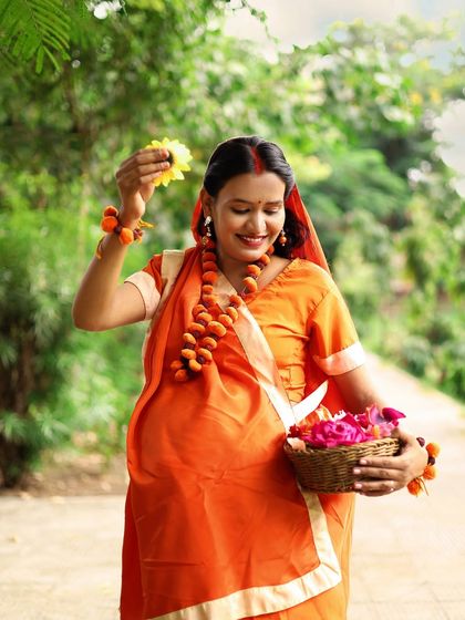 A solo portrait of the mother-to-be, dressed as Sita, with a basket of flowers. Her joyful expression and the traditional attire make this a beautiful, devotional image.
