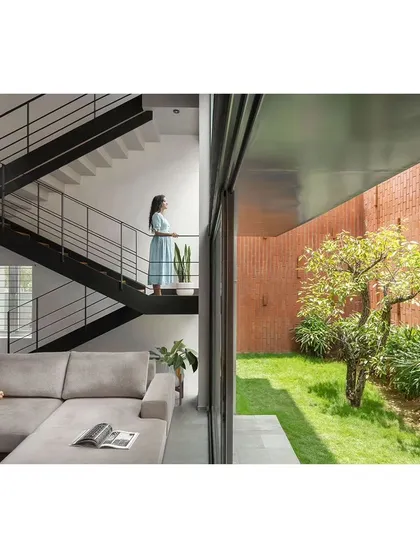 The split-level design allows for clear sightlines across the home. Here, standing on the staircase landing, you can look down into the living area and directly out into the garden, which is enclosed by a high brick wall for complete privacy.