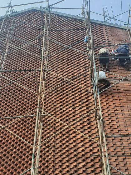 The intricate brick facade of the Brick House required immense skill and patience. This site photo shows our team of artisans carefully placing each brick to create the complex, woven pattern that defines the building's character.