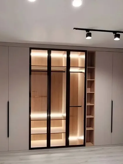 This wardrobe design is a showstopper, combining solid and glass doors with internal lighting. The central glass display is perfect for showcasing your favorite accessories, while the side cabinets offer ample concealed storage.