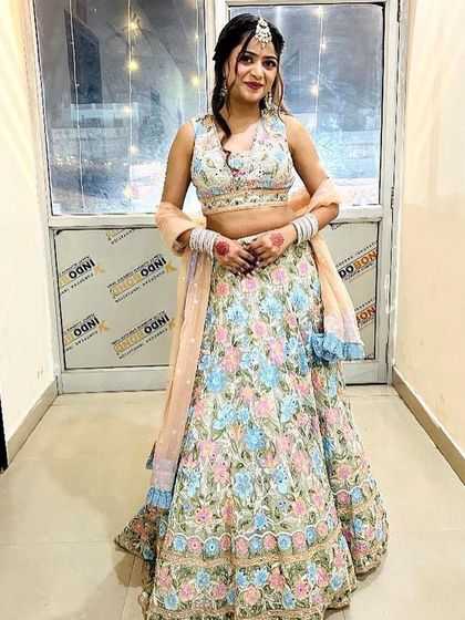 A full-length view of a client in the pastel floral lehenga. The combination of light blue, pink, and peach makes it a fresh and pretty choice.