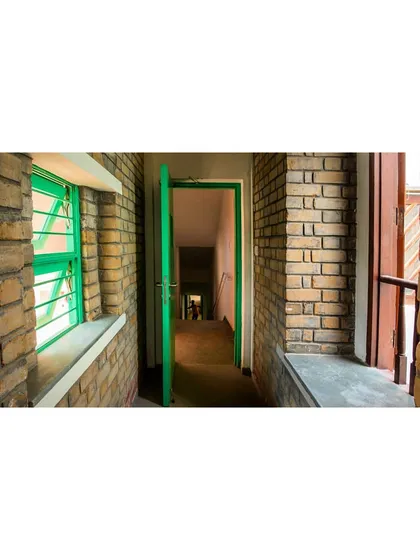 A view down a corridor lined with the same earth blocks. The material provides excellent thermal mass, helping to keep the interiors cool in summer and warm in winter, reducing the need for artificial heating or cooling.
